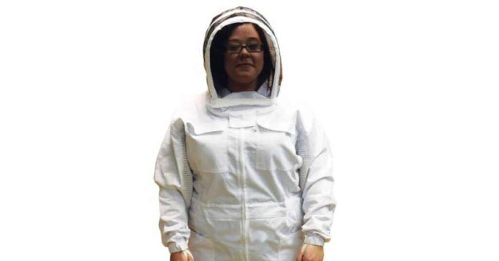 A person in a white beekeeping jacket with an attached veil and protective hood.